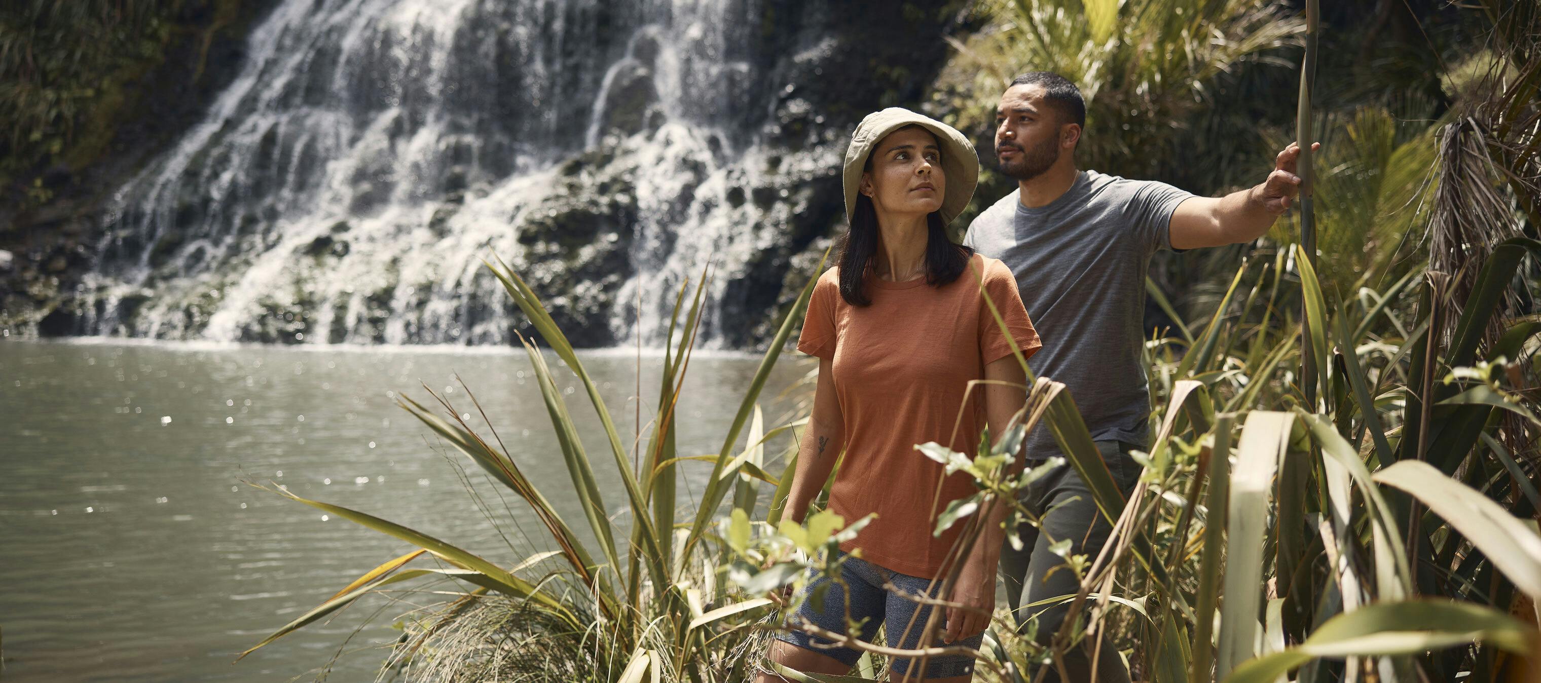 a man and woman doing what they love: exploring nature around a beautiful waterfall