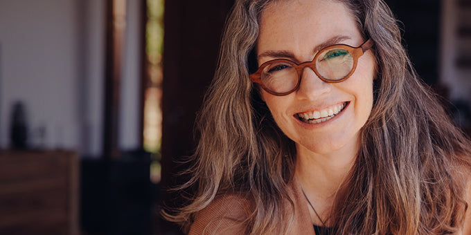 Happy middle-aged woman wearing glasses with a blurred indoor background