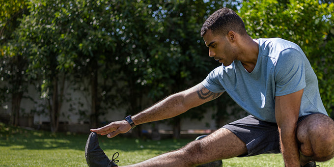 Man stretching legs outdoors with trees in the background