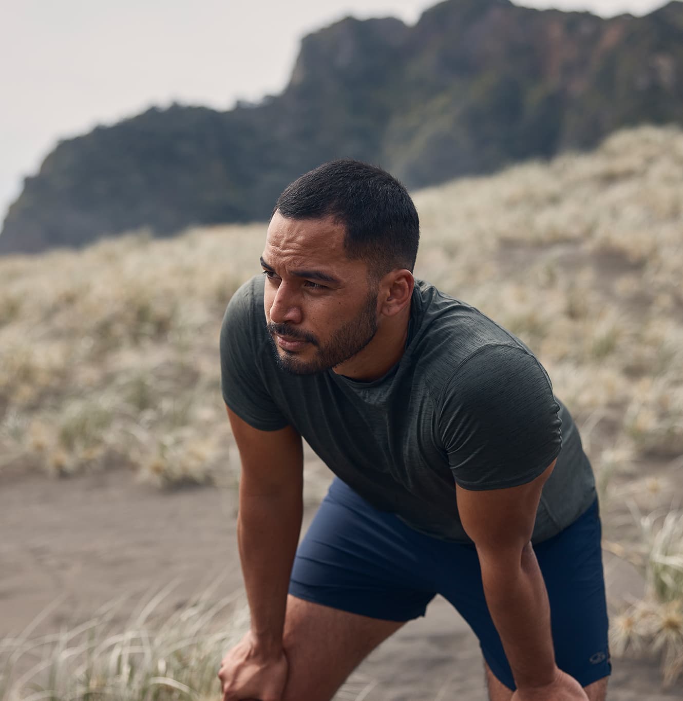 a man temporarily recovering from his run outside on the beach