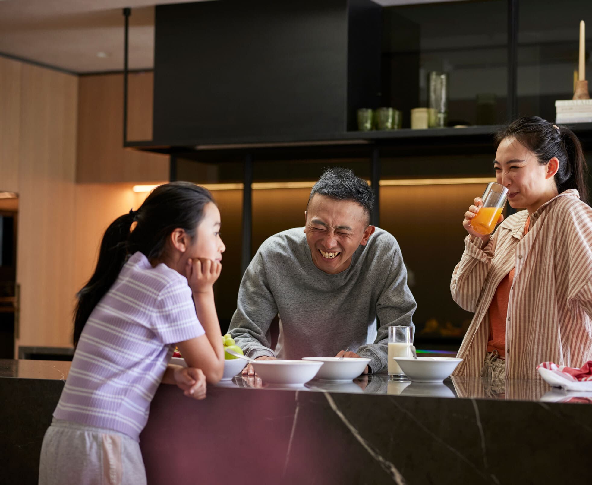 a family of 3 enjoying a meal together in their kitchen