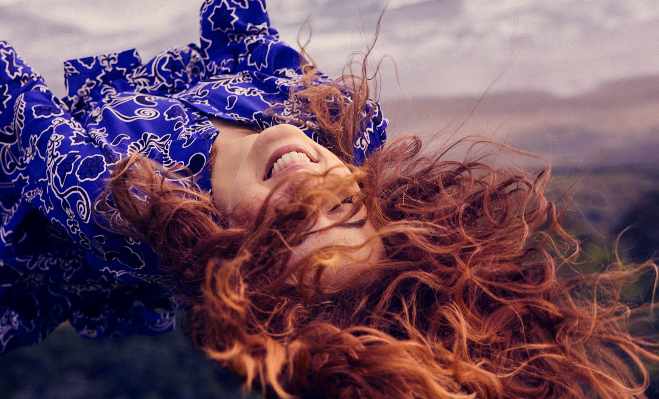 a woman smiling while enjoying her time on a swing outside
