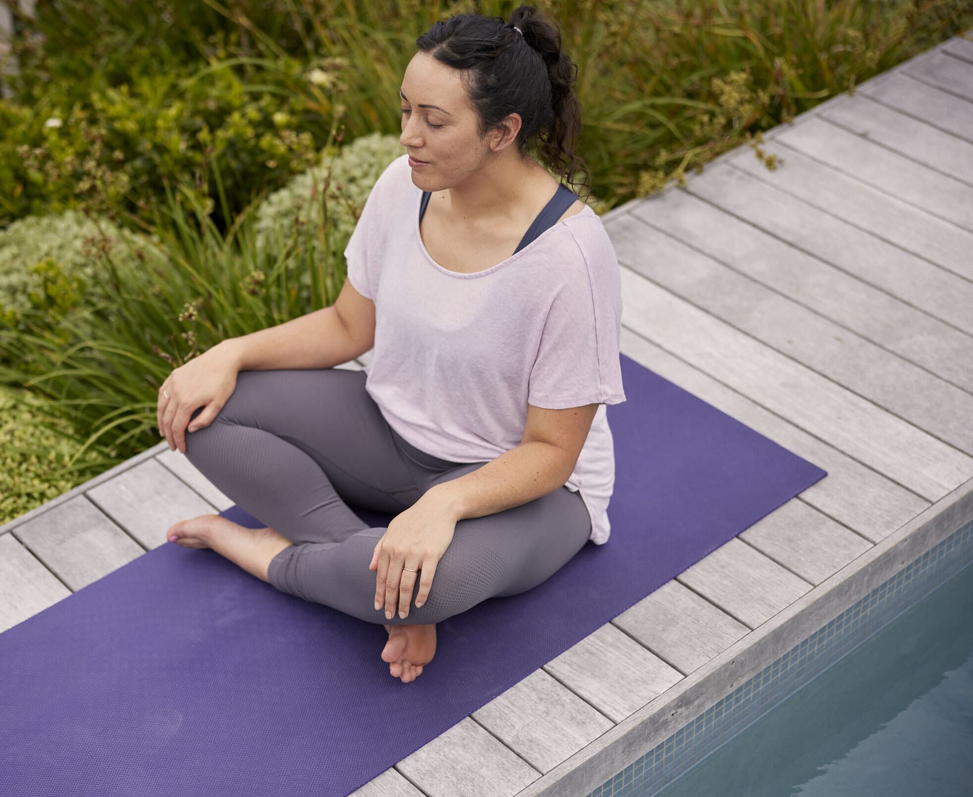 Woman doing yoga by pool