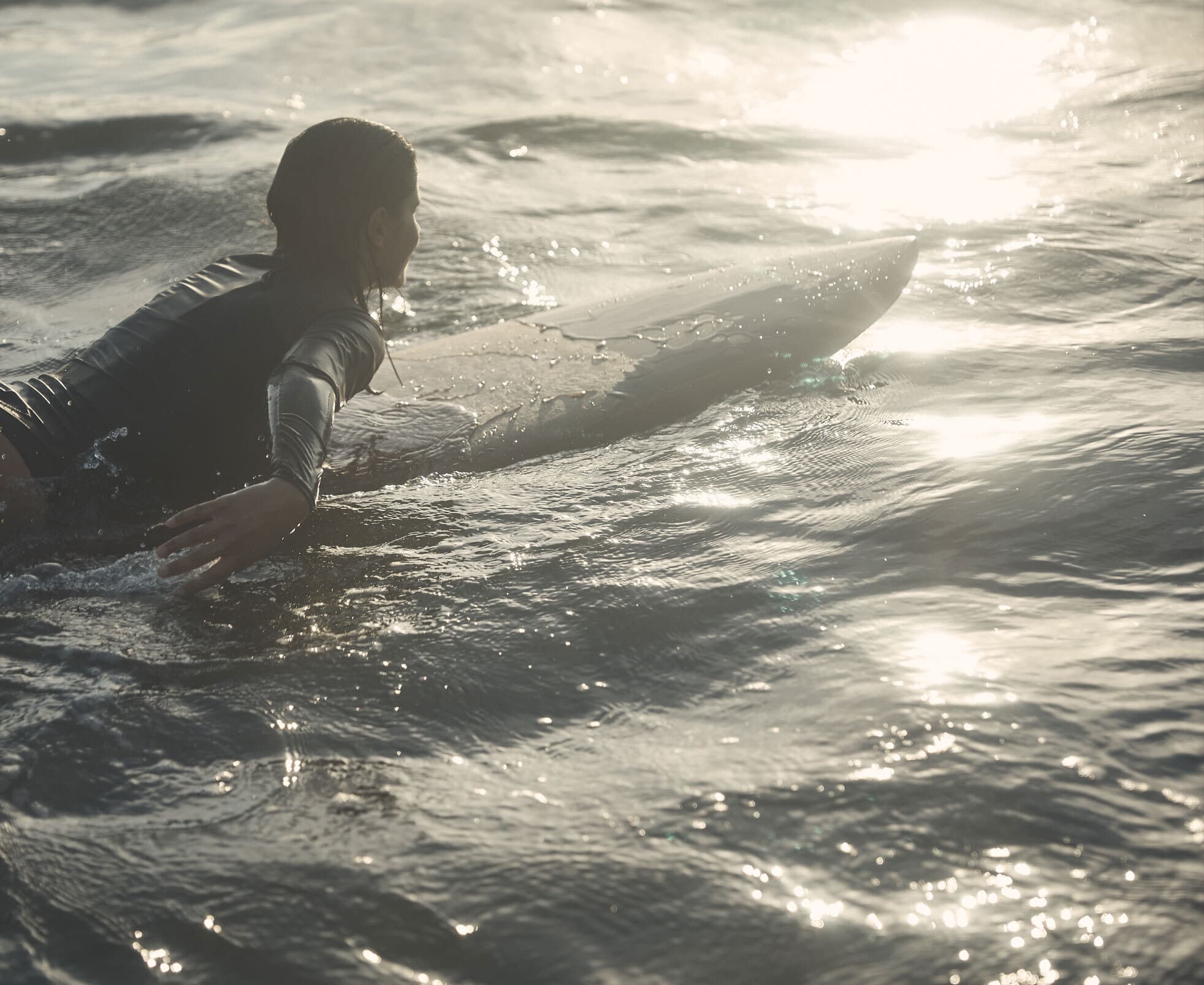 Woman heading out to surf as the sun rises