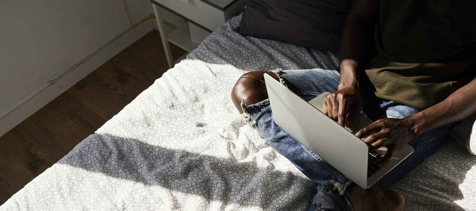 man working on laptop in bed