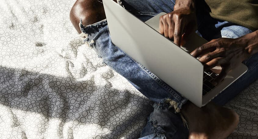 Man working on laptop in bed