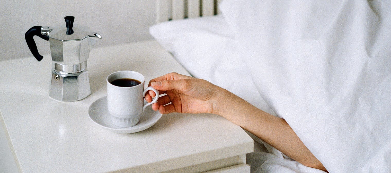 Cup of coffee next to bed