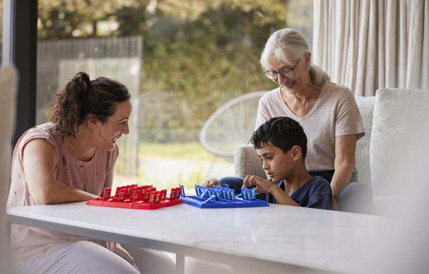 Mother, grandmother and son playing board games