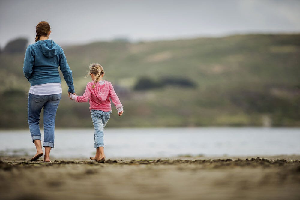 Mum and daughter walking at beach