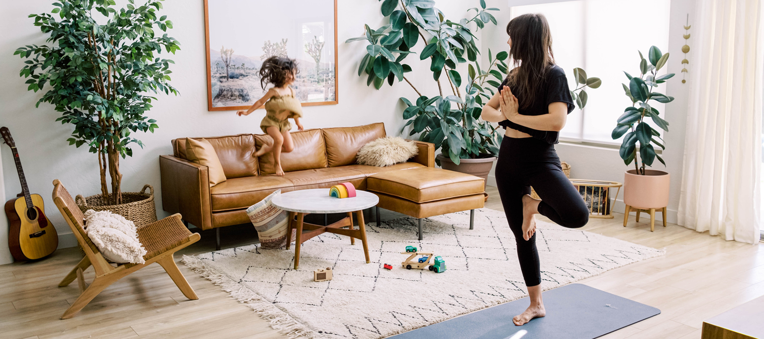 Mum doing yoga in living room while daughter is playing