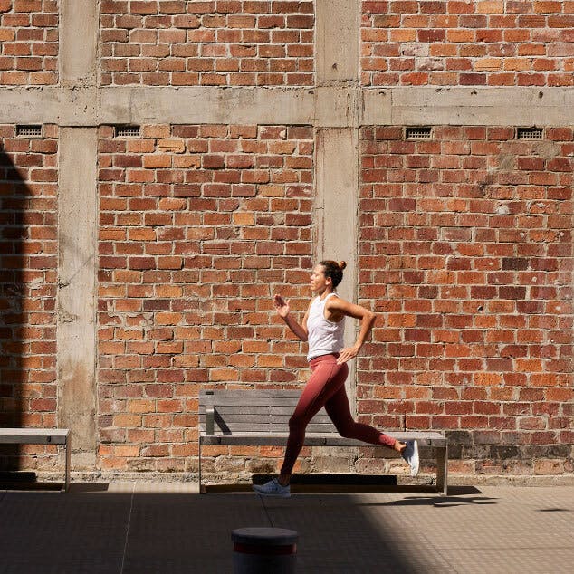 Lady running outside past a brick building