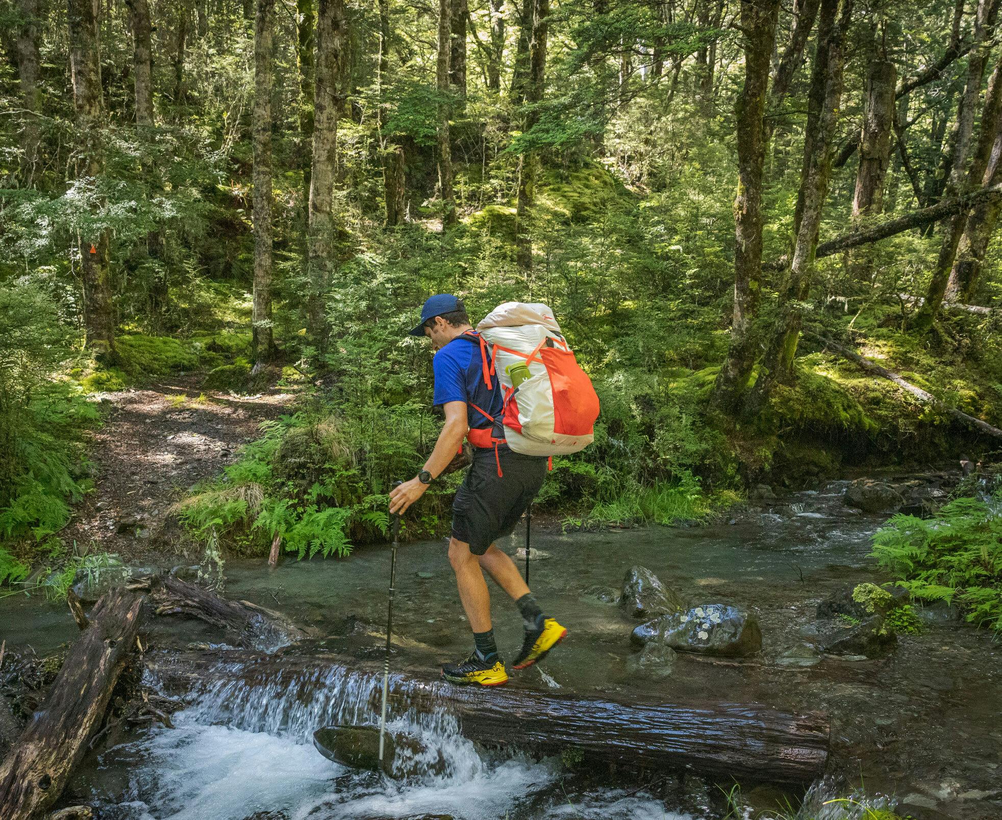 a backpacker enjoying a hike over a stream in the woods
