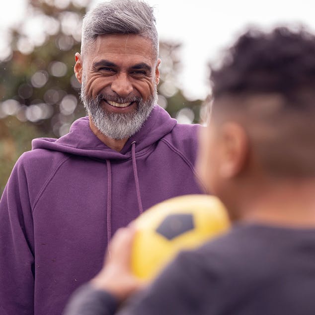 Man smiling playing soccer with son
