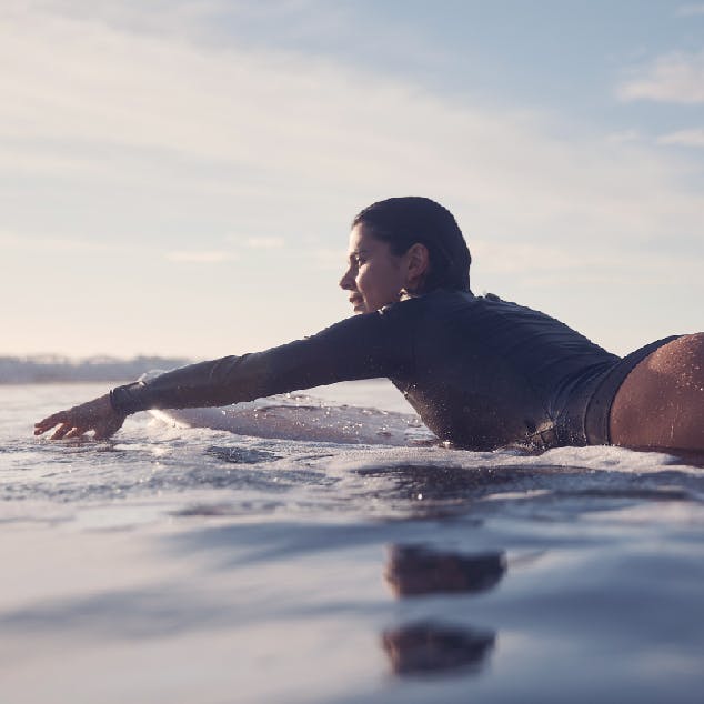 Lady swimming with surfboard at beach