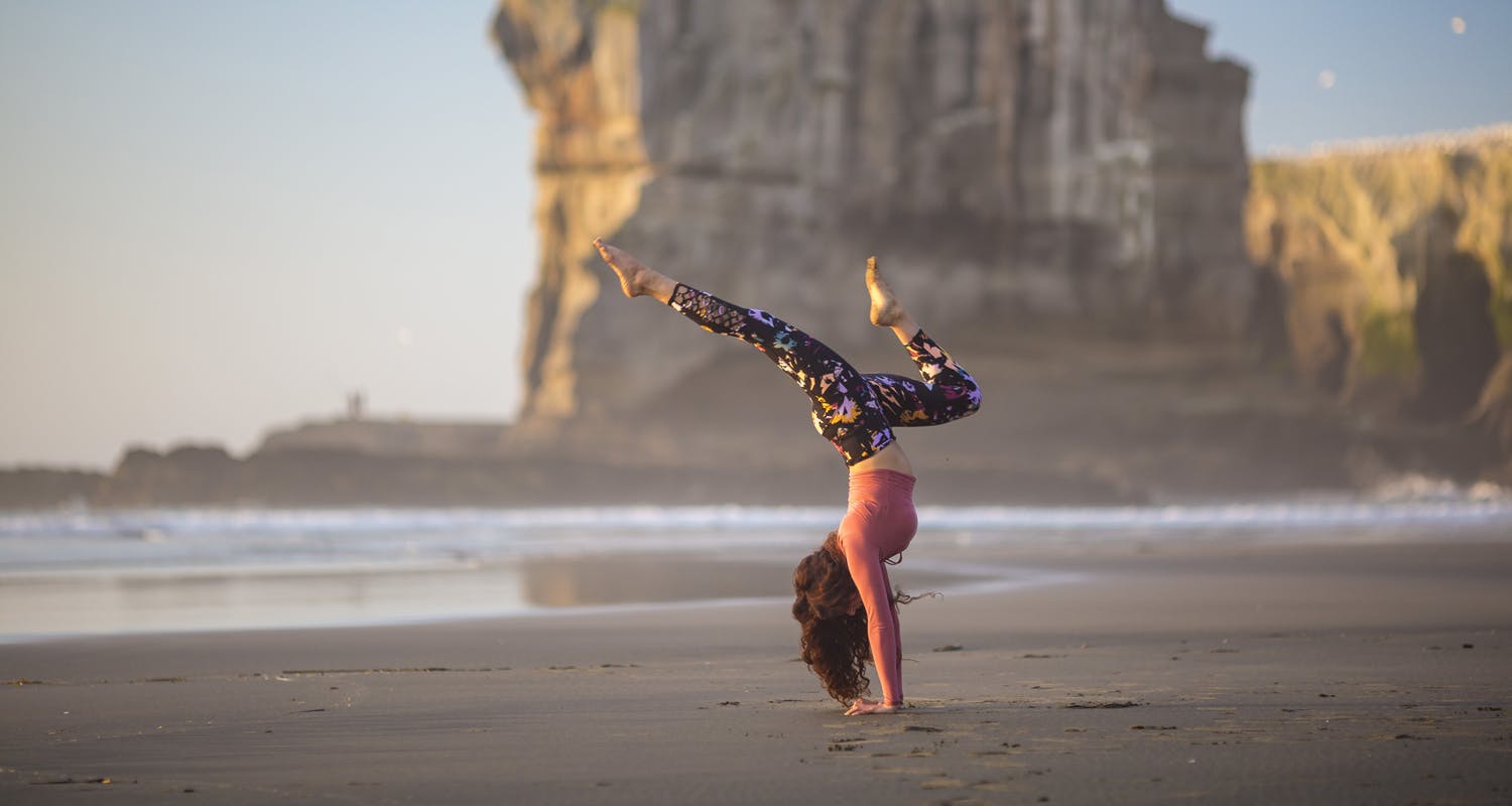 Woman doing a handstand at the beach