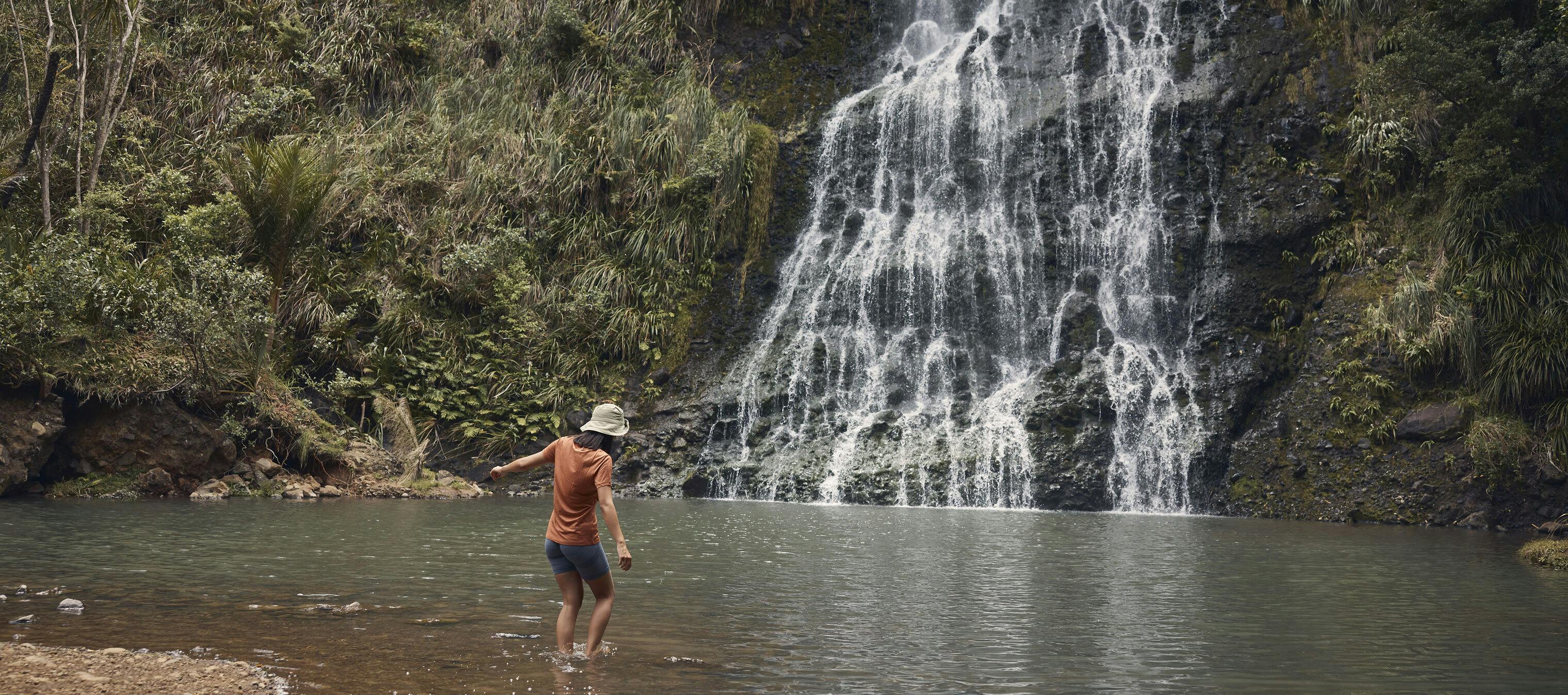 A woman walking up to a beautiful natural waterfall