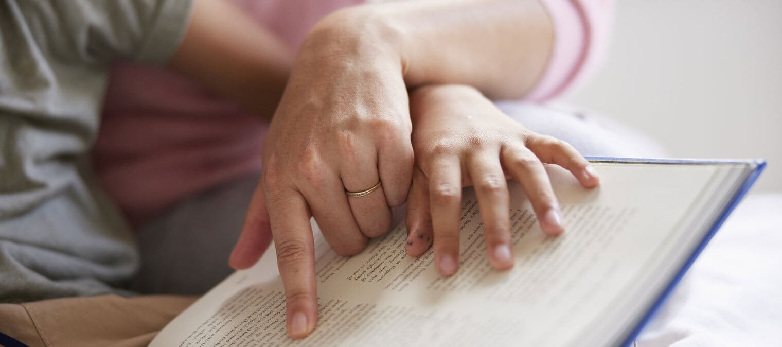 Mother and son reading book close up on hands