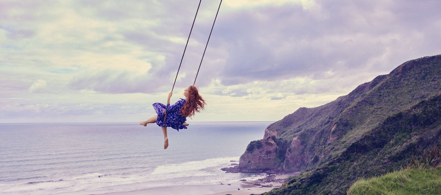 Woman on a swing above the ocean