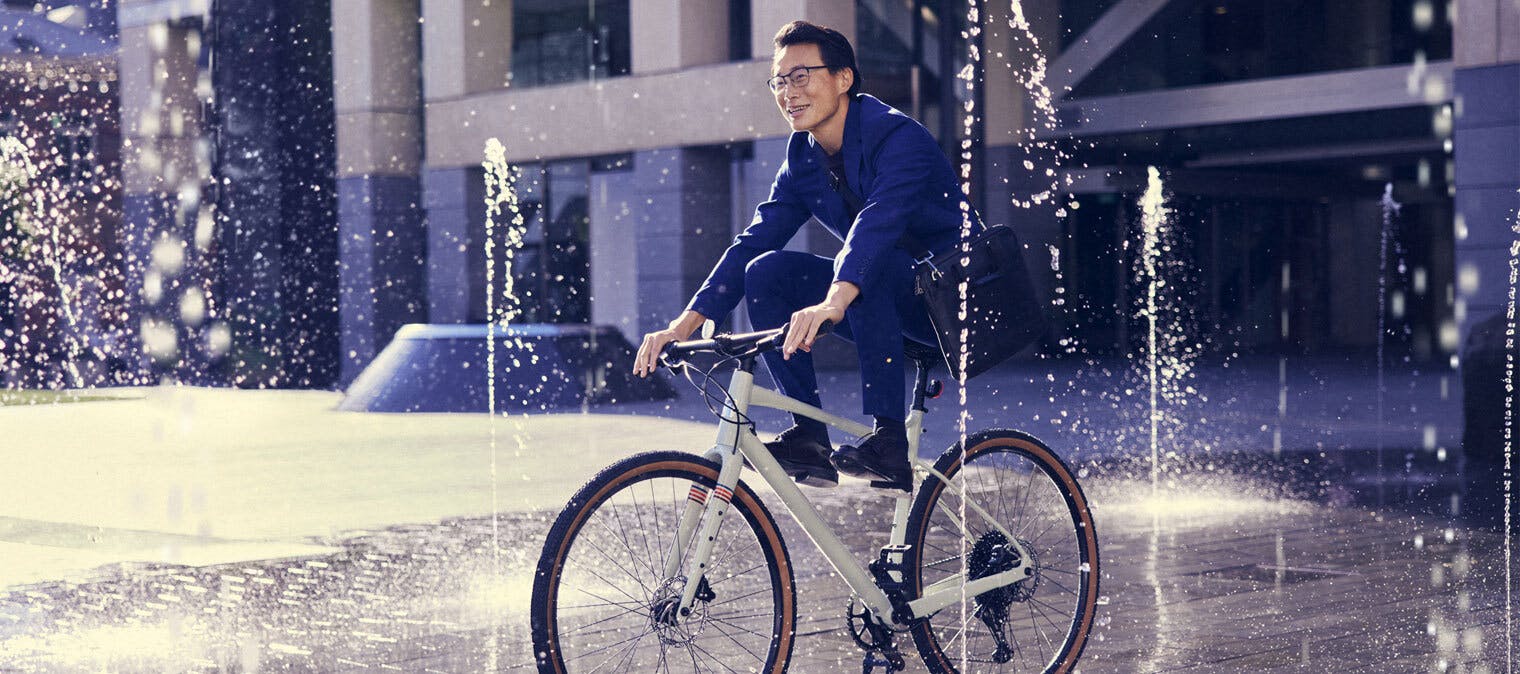 Man riding bicycle through sprinklers