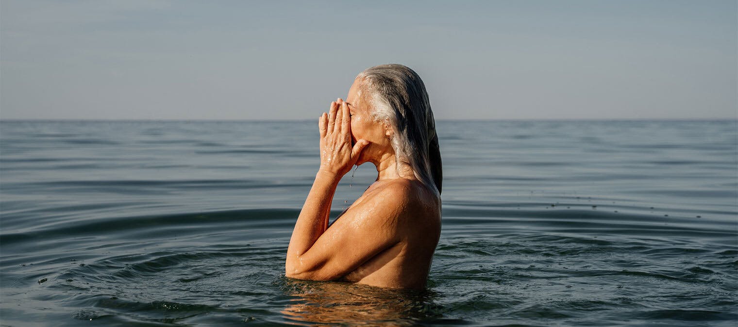 Lady wiping eyes while in the water at the beach