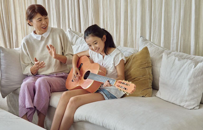 Grandaughter playing guitar while her grandmother watches