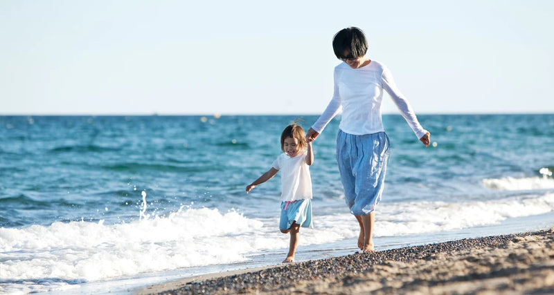 Woman running with child on beach