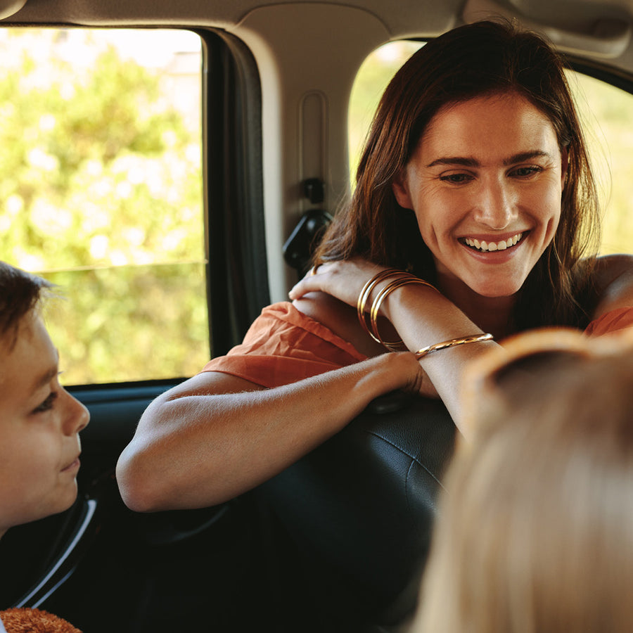 Mom looking to the backseat of her car with her 2 kids