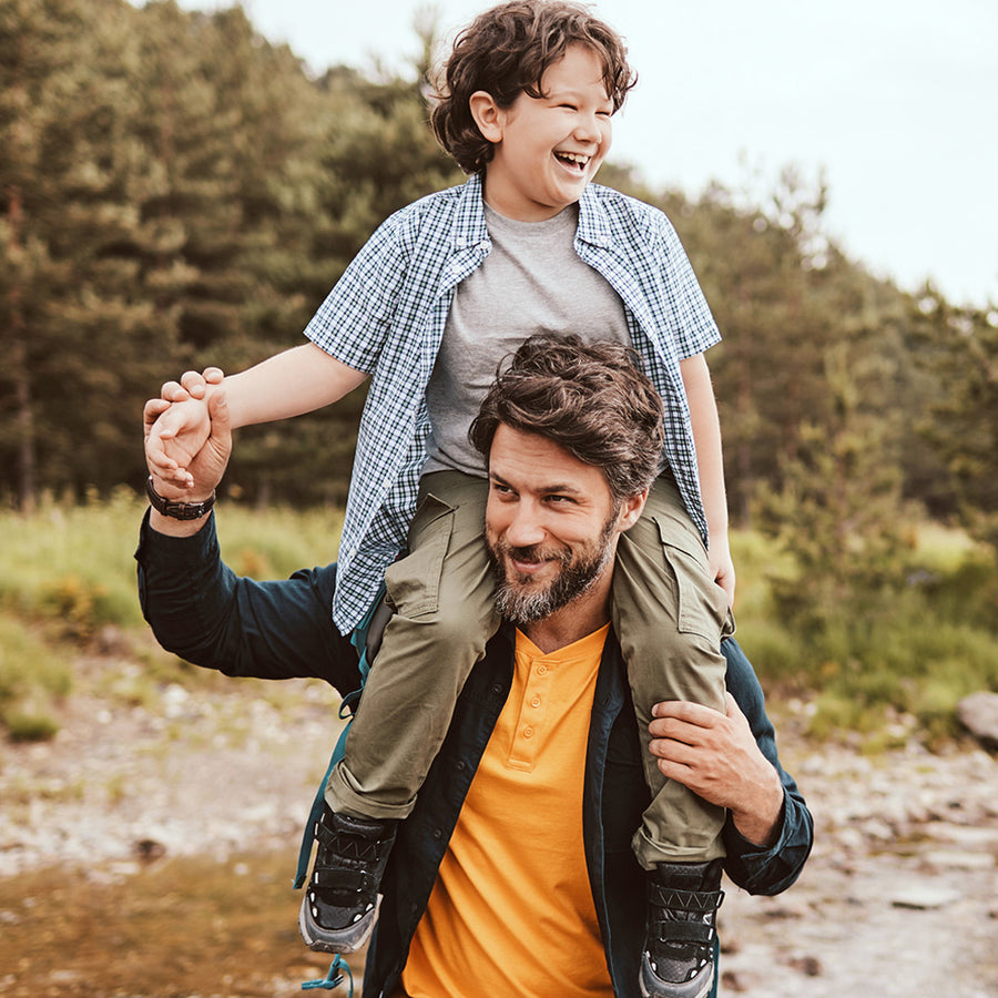 son on his dad's shoulders in the wilderness