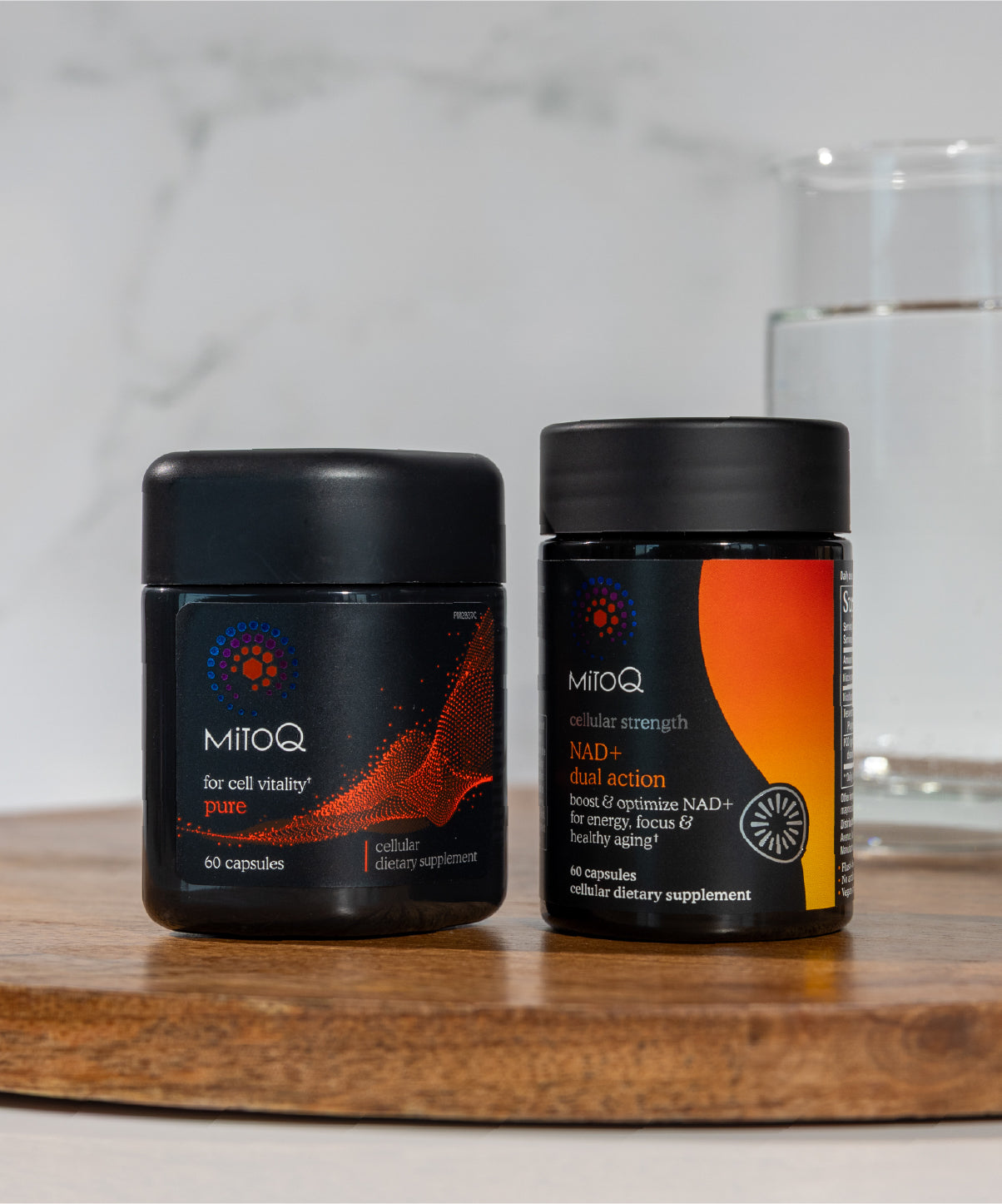 Two MitoQ supplement containers (MitoQ Pure and MitoQ NAD+ dual action) on a wooden surface with a blurred background