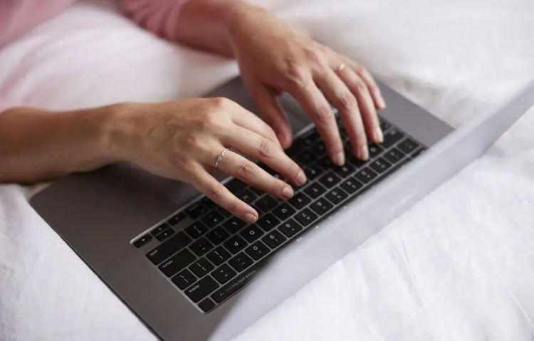 Person typing on a laptop keyboard with a white background